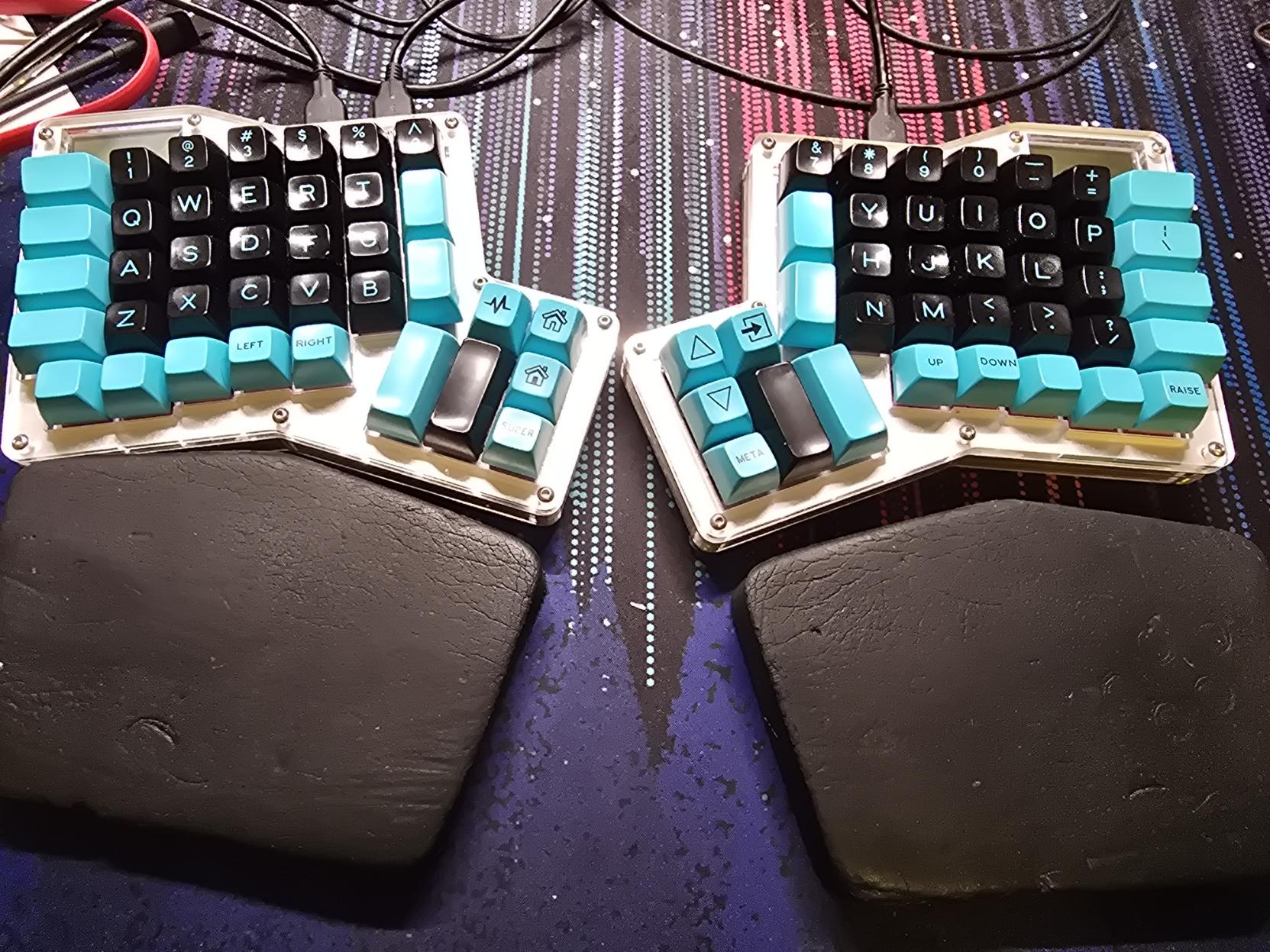 A photo of my keyboard: an Input Club Infinity Ergodox, which is a split ortholinear layout. The letter and number keys are black with blue labels, other keys are blue with black labels