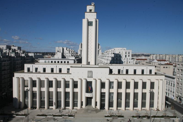 The Villeurbanne Town Hall (1934) by Lyon architect Robert Giroud. A wide, pretty angular white building with a facade alternating tall columns and glass, including a tall bell tower in the middle.