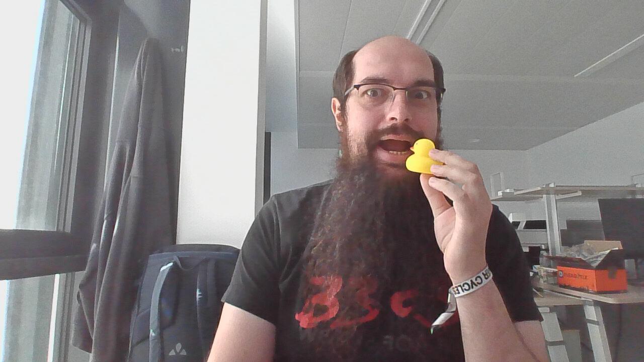 A Debian Developer, uploading (me, a balding white man with glasses and a long beard) ready to eat a rubber ducky, as a treat